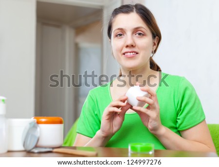 woman caring for face with cosmetics at home