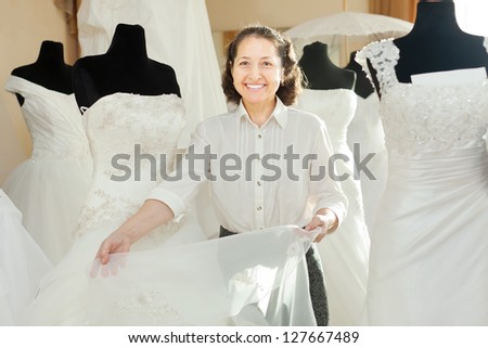 Woman shows bridal gown at shop of wedding fashion