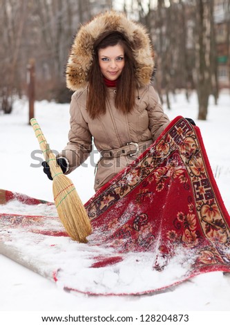 Young woman cleans red carpet with snow