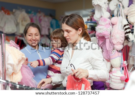 Two women and child chooses clothes at store. Focus on woman