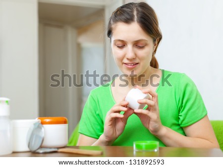 woman caring for  face with cosmetics at home interior