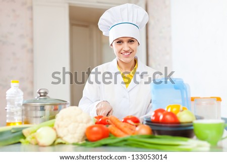 cook woman  in uniform cutting vegetables  at commercial kitchen