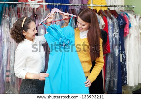 Two women chooses blue evening gown  shop of fashionable clothes