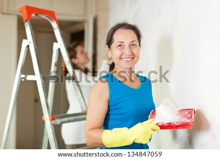 Happy women makes repairs in the apartment together