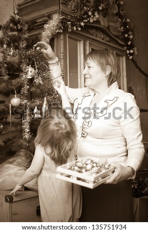 Mature woman  and child preparing for  Christmas at home. Imitation of an old photo