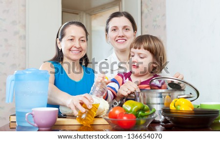 happy women with child cook vegetables in kitchen
