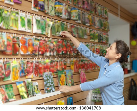 Smiling  woman chooses the seeds at store for gardener