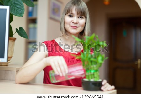 Young woman with lucky bamboo plant at her home
