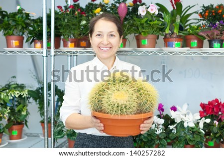 woman in flower shop near the shelves with cactus