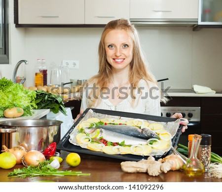 pretty woman cooking fish and potatoes in sheet pan