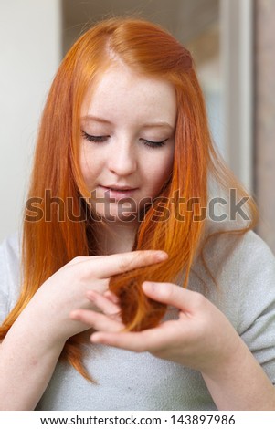teen girl looks at the tips of his hair
