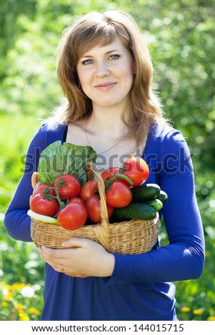 Happy girl with vegetables harvest in garden