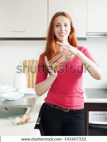 Positive woman in red cleaning glass bottle with egg shell