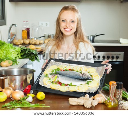 Ordinary housewife cooking fish and potatoes in sheet pan