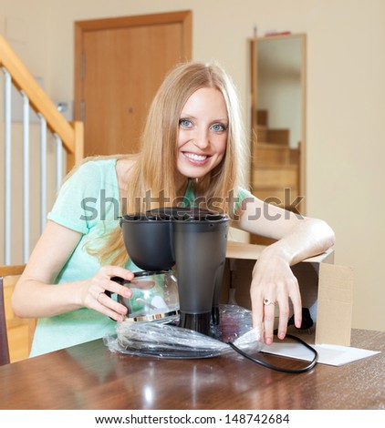 Cute young blond with new  coffee maker in home in living room