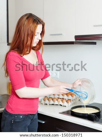 woman making scrambled eggs in frying pan