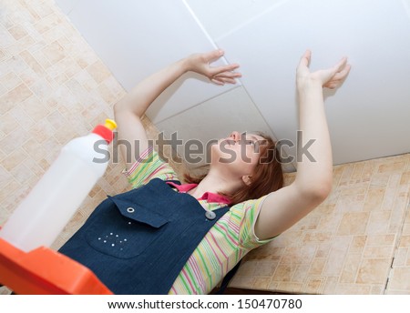 Young woman glues ceiling tile at home