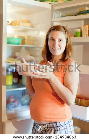 pregnant woman with pan near refrigerator  at home