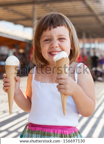 Portrait of happy 3 years baby girl eating ice cream at cafe in summer