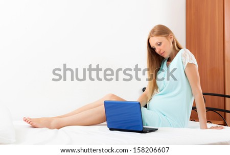 Sitting pregnant woman  awaking with blue laptop