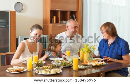 Smiling three generations family posing together over healthy table at home interior