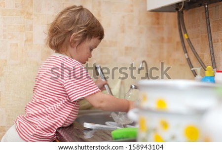 Baby girl  washes dishes in kitchen