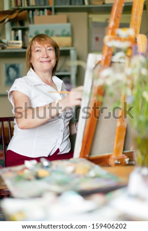 Female artist paints a picture on canvas with oil paints