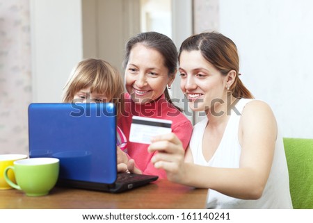 Happy family of three generations paying by credit card in internet store at home