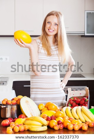 Happy  long-haired woman with melon and other fruits in home