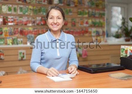 friendly mature woman selling seeds in store for gardeners