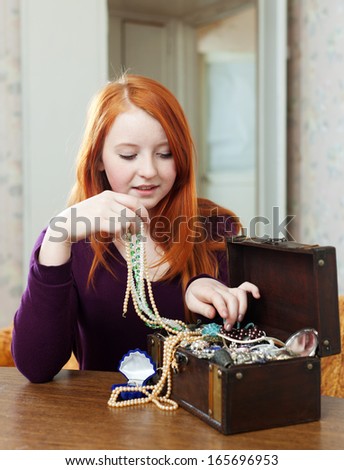 teen girl looks jewelry in treasure chest at home interior