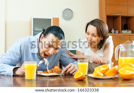 Happy couple having breakfast with scrambled eggs and oranges in morning after night together