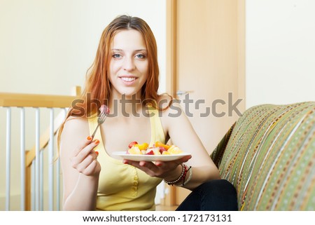 positive red-hair girl eating fruits salad