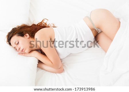 Pretty girl in white shirt sleeping on white pillow in bed at home