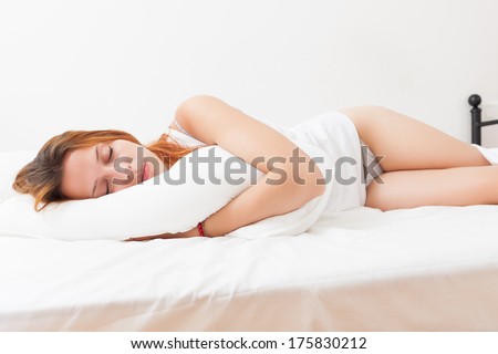 Red-haired girl sleeping on a white pillow in bed at home