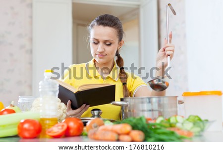 Woman cooking  veggie food with book at domestic kitchen