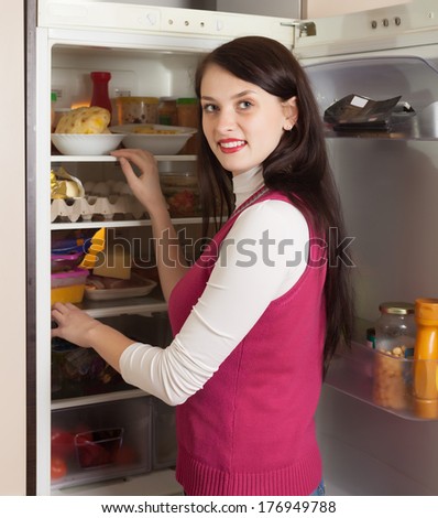 Brunette woman looking in refrigerator  at home