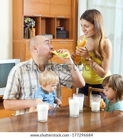 happy family of four  having lunch with sandwiches at home together