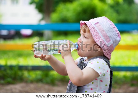 2 years child drinks from plastic bottle in park
