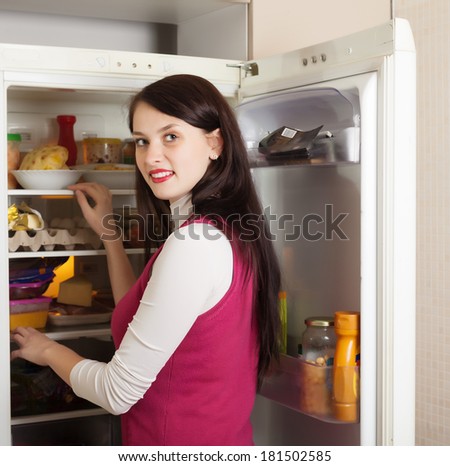 Brunette woman looking for something in refrigerator  at home