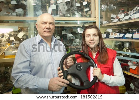 mature man and woman with  steering wheel  in  auto parts store