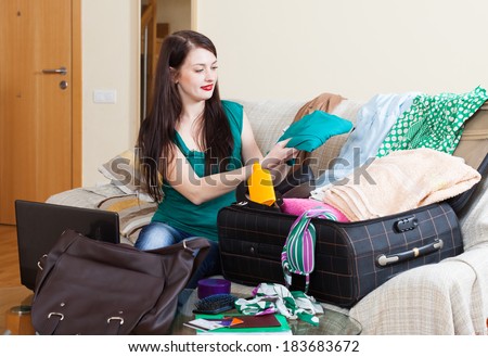 female traveler packing suitcase for holiday at home