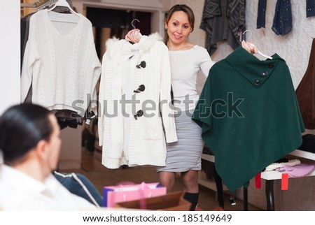 Smiling couple trying coat in fitting-room at clothing store