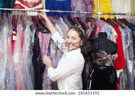 Happy mature woman  chooses evening gown at clothing store
