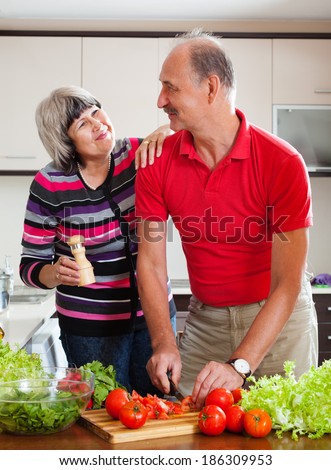 happy elderly couple cooking veggy lunch in  kitchen