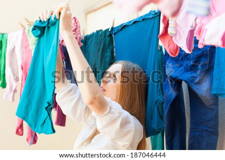 housewife drying clothes on clothes-line after laundry