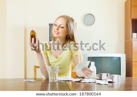 Long-haired blonde woman with medications at table in living room