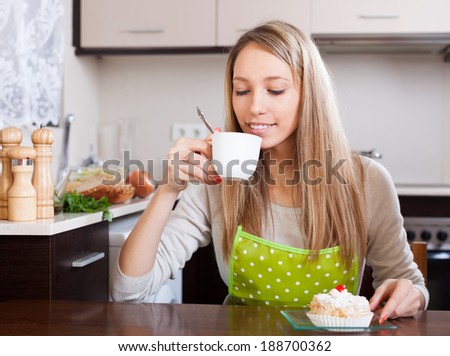 Housewife  drinking tea with cake in home kitchen