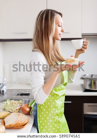 Woman  with cakes and tea in home kitchen