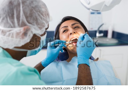 Portrait of female patient during dental checkup in modern dentist office. Health care and oral hygiene concept Foto d'archivio © 